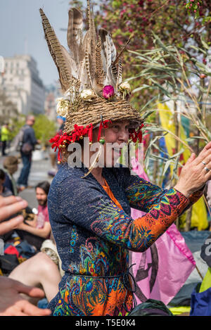 Rébellion Extinction protester sur Waterloo Bridge, habillés de couleurs vives femme avec beaucoup de plumes dans son chapeau claque, Londres, UK Banque D'Images