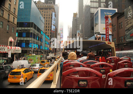 Les touristes sur un double-decker tour bus roulant sur 7e Ave en direction de Times Square à Manhattan, New York, USA. Banque D'Images