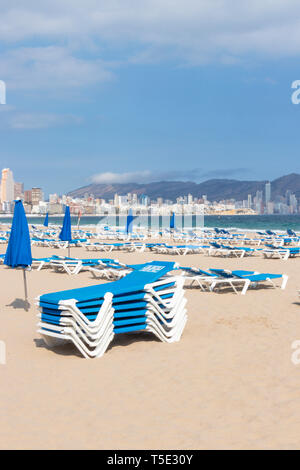 Chaises longues bleu empilés sur plage vide à Alicante, Espagne Banque D'Images
