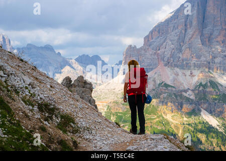 Jeune femme en randonnée dans les montagnes des Dolomites, l'Italie, le Giro delle Cinque Torri, avec les nuages de tempête approche à grands pas. L'orientation, la randonnée dans les montagnes. Banque D'Images