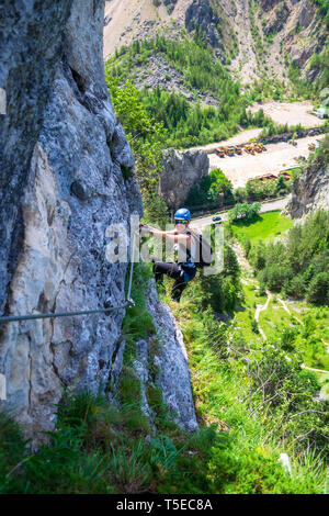 Femme climber hanging from une via ferrata cable sur 'Astragalus' route, une attraction touristique populaire dans les gorges de Bicaz (les gorges du Bicaz), Neamt, R Banque D'Images