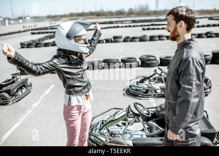 Happy female driver avec instructeur sur la piste de karting en plein air Banque D'Images