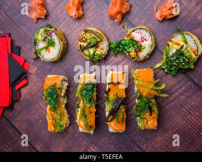 Tableau a servi avec sushi sur fond sombre. Rouleaux de sushi, wasabi, gingembre, wakame frais généraux, la cuisine japonaise traditionnelle Banque D'Images