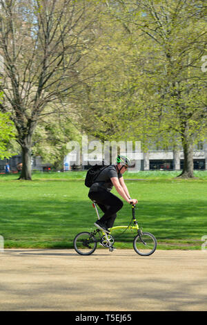 Rider sur vélo pliant brompton vert, Hyde Park, Londres, Royaume-Uni Banque D'Images