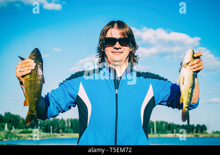 Pêcheur heureux montrant poisson frais. Caucasian man détient deux poissons. Pêcheur pour la pêche en rivière Banque D'Images