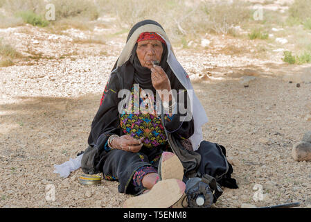 Israël, désert du Néguev, mature bédouine en vêtements traditionnels fume une pipe Banque D'Images