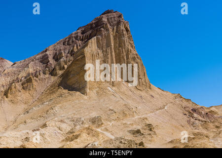 Un sentier de randonnée traverse la base d'un pic de montagne désert élevé dans un vaste paysage de désert coloré - Manly Beacon dans Death Valley National Park Banque D'Images