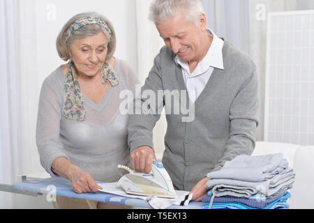 Happy senior couple posing et pendant le repassage à la maison Banque D'Images