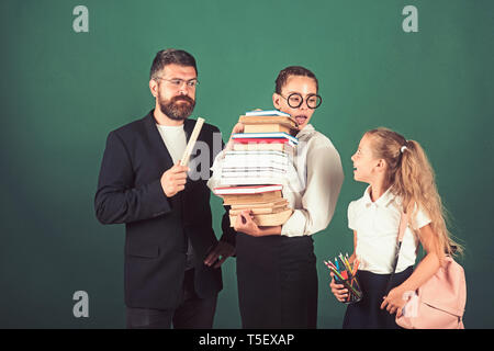 Processus de formation avec de nombreux livres dans les mains des filles avec l'enseignant. formation à l'interrogatoire à l'école Banque D'Images