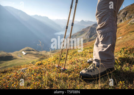 Des bâtons de marche et des chaussures de randonnée, avec vue sur le barrage de Tignes, la bergerie et le refuge de la Martin, dans le Parc National de la Vanoise, Taren supérieur Banque D'Images