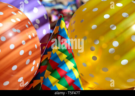 Papier coloré parsemé de ballons et chapeau dans la lumière vive dans premier mai Banque D'Images