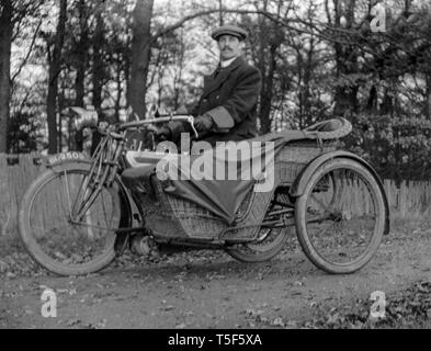 Une période photo d'un homme assis sur une moto Triumph vintage et side-car. Du côté de la voiture est faite à partir de l'osier. Banque D'Images