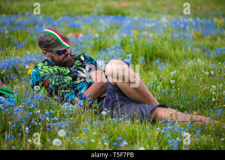 Un jeune homme se détend allongé sur une clairière couverte de fleurs. L'heure d'été. L'homme en short, t-shirt, chapeau et lunettes de soleil Banque D'Images