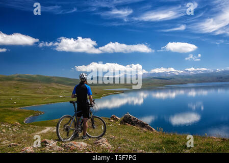 Un jeune homme avec un vélo sur l'arrière-plan de la haute montagne lac Sonkol. Kirghizistan. Vue depuis l'arrière Banque D'Images