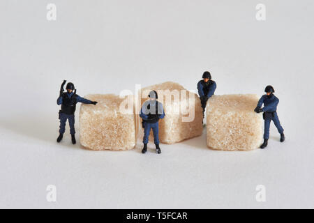 Figurines représentant les agents de police entourant le sucre forfaitaire : la protection et la sécurisation de la marché mondial du sucre Local Caption *** *** Banque D'Images