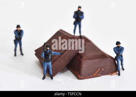 Figurines représentant les agents de police entourant les morceaux de chocolat : la protection et la sécurisation de la légende locale du marché du chocolat *** *** Banque D'Images