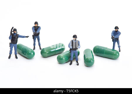 Figurines représentant les agents de police entourant les capsules, la drogue : la protection et la sécurisation du marché pharmaceutique Local Caption *** *** Banque D'Images