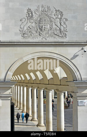 Les touristes se promener en dessous des armoiries au Royal Opera House shopping arcade avec colonnade faisant partie de l'immeuble à Covent Garden London England UK Banque D'Images