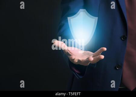 Businessman With glowing icône de bouclier sur fond sombre. Concept de sécurité des données Banque D'Images