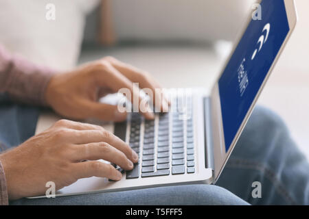 Jeune homme avec ordinateur portable à l'aide d'une connexion Wi-Fi gratuite, gros plan Banque D'Images