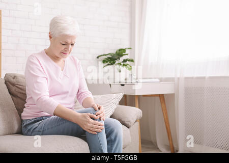 Hauts femme souffrant de douleur dans la jambe, en massant son genou Banque D'Images