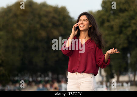 Cheerful student fille parlant sur cellule dans city park Banque D'Images