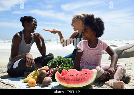 Mère et fille avec tes amis faire un pique-nique sur la plage Banque D'Images