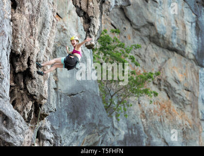 La Thaïlande, Krabi, Lao Liang, happy woman climbing in rock wall Banque D'Images