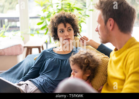 Family lying on couch watching movie sur theit tablet Banque D'Images