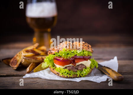 Hamburger fait maison avec une salade verte sur fond de bois brun. Banque D'Images