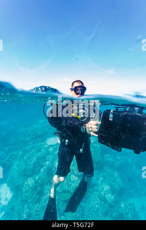 Cameraman plongeur dans l'eau avec de l'équipement, au-dessus de la flottaison au-dessous de l'équipement préparation à descendre à 3D camermera avec film Banque D'Images