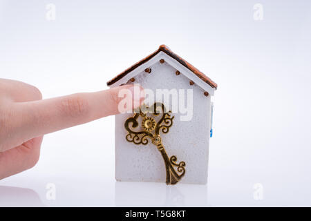 Main tenant une clé d'or près d'une maison sur un fond blanc Banque D'Images