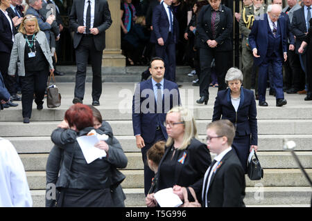 Belfast, County Antrim, Northern Ireland, 24 avril, 2019 - Premier ministre britannique Theresa May et Taoiseach Irlandais, Leo Varadkar regardez sur la famille en tant que parents de Mme Lyra McKee hug à l'extérieur à St Anne's Cathedral, Donegall Street, Belfast après les funérailles de Mme McKee. Mme McKee, un des journalistes, 29, a reçu une balle dans la tête jeudi soir tout en observant des émeutes au Cœur du domaine Creggan. La nouvelle IRA a admis la responsabilité de l'assassinat du journaliste Lyra McKee. Paul McErlane/Alamy Live News Banque D'Images
