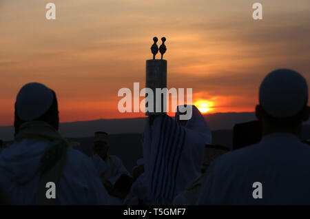 25 avril 2019, les territoires palestiniens, à Naplouse : un prêtre Samaritain soulève la Torah en tant que membres de la communauté Samaritaine recueillir au sommet du mont Garizim, d'assister à un matin tôt Pâque prières pour marquer la fin de la Pâque, maison de vacances, près de la ville cisjordanienne de Naplouse. Les Samaritains, un groupe de caractère ethnoreligieux du Levant provenant d'Israël, ou des Hébreux, de l'Orient ancien, affirment descendre de la tribu d'Éphraïm et de la tribu de Manassé (deux fils de Joseph). Selon la Torah, le Sacrifice de la Pâque a été offert pour la première fois la nuit de l'exode des Israélites de l'Égypte. Banque D'Images