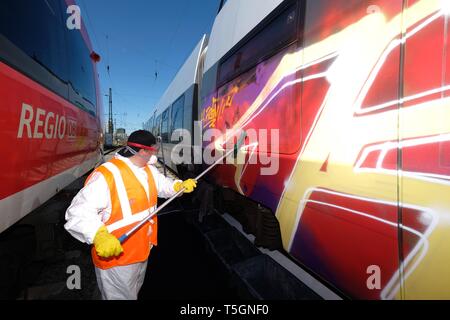 Leipzig, Allemagne. Apr 25, 2019. Un Décapant pour graffitis travaille sur un S-Bahn pulvérisé voiture à la gare centrale de Leipzig. Credit : Sebastian Willnow/dpa-Zentralbild/dpa/Alamy Live News Banque D'Images