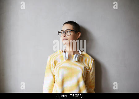 Portrait de jeune femme aux cheveux courts portant des lunettes et des écouteurs Banque D'Images
