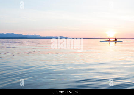 Les femmes personnes kayak de mer Bateau canotage en eau calme au coucher du soleil. L'aventure de plein air active sports d'eau. Voyage, la destination, l'équipe repose. Banque D'Images