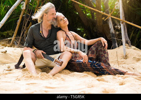 Portrait of happy senior couple hippie avec guitare détente sur la plage Banque D'Images
