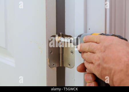 Visseuse metal chrome installation charnières sur un processus de porte en bois Banque D'Images