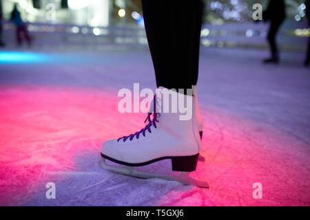 Jambe de femme portant des patins à glace sur une patinoire Banque D'Images