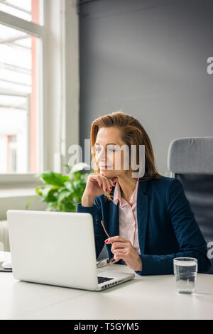 Businesswoman sitting in office, working on laptop Banque D'Images