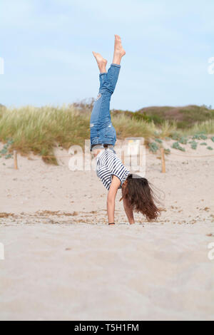 L'Espagne, Minorque, barefoot young woman doing handstand sur la plage Banque D'Images