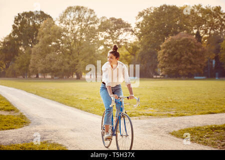 Young woman riding bike dans un parc Banque D'Images