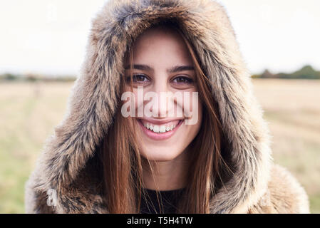Portrait of happy young woman wearing fur hood Banque D'Images