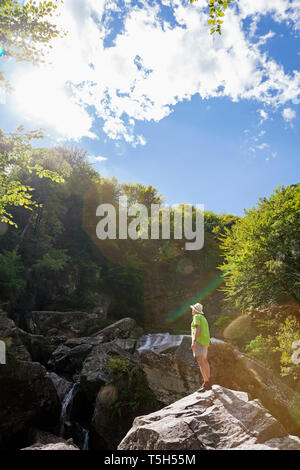 La Suisse, la vallée de Verzasca, Tessin, l'homme debout sur la roche à la cascade à Banque D'Images