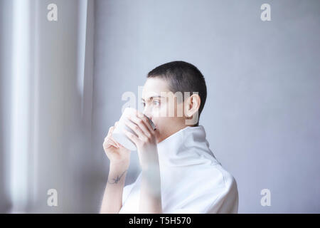 Portrait of short-haired young woman drinking from mug Banque D'Images