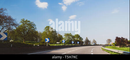 Flèches bleues sur l'autoroute de l'autoroute avec un van roulant en arrière-plan Banque D'Images