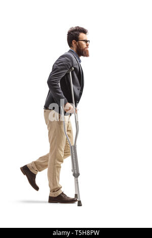 Profil de pleine longueur de balle un jeune homme barbu à marcher avec des béquilles isolé sur fond blanc Banque D'Images