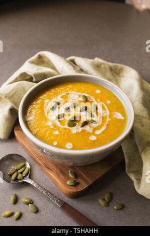 Un bol de soupe au potiron avec une cuillère et serviette et graines de citrouille Banque D'Images