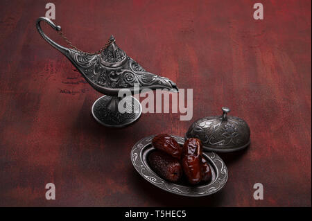 Plaque d'argent avec les dates et la lampe d'Aladdin rouge foncé sur fond de bois. Ramadan arrière-plan. Ramadan kareem. Banque D'Images